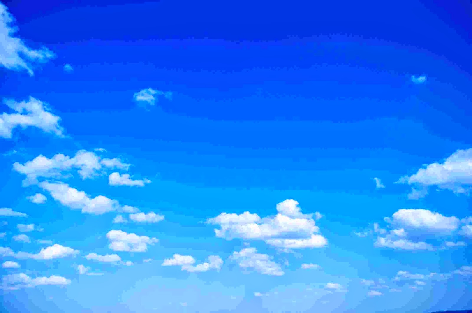 Bright blue sky with scattered white fluffy clouds, calm and airy mood